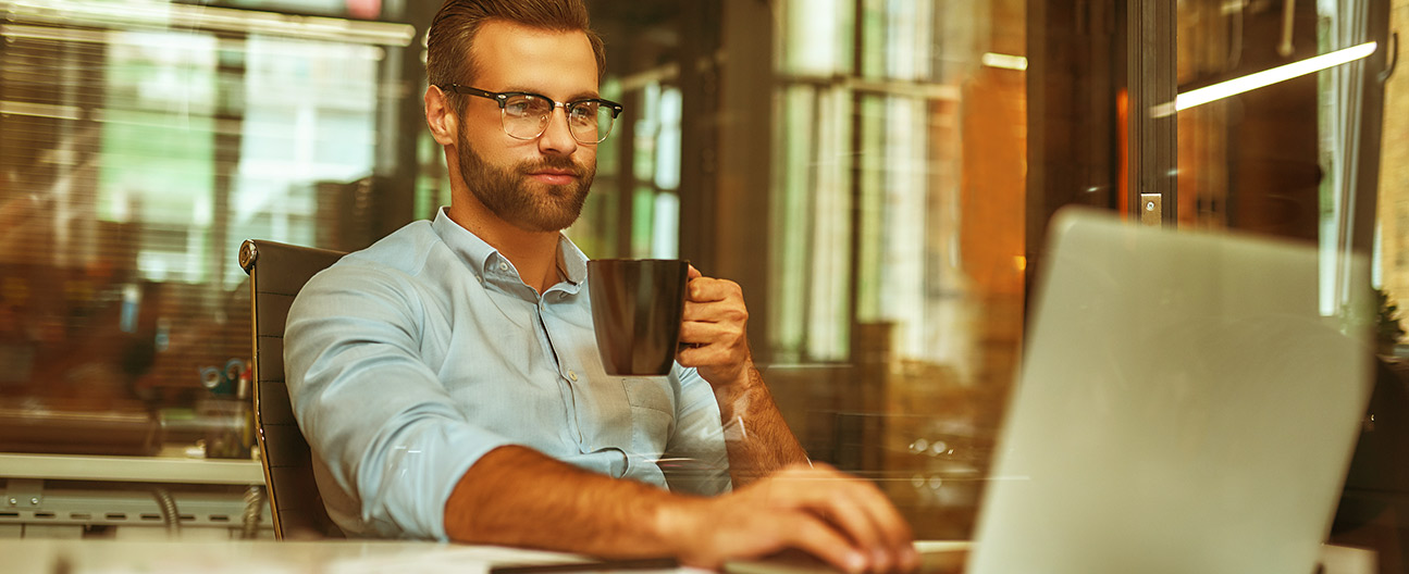 A man working on a laptop while having coffee.