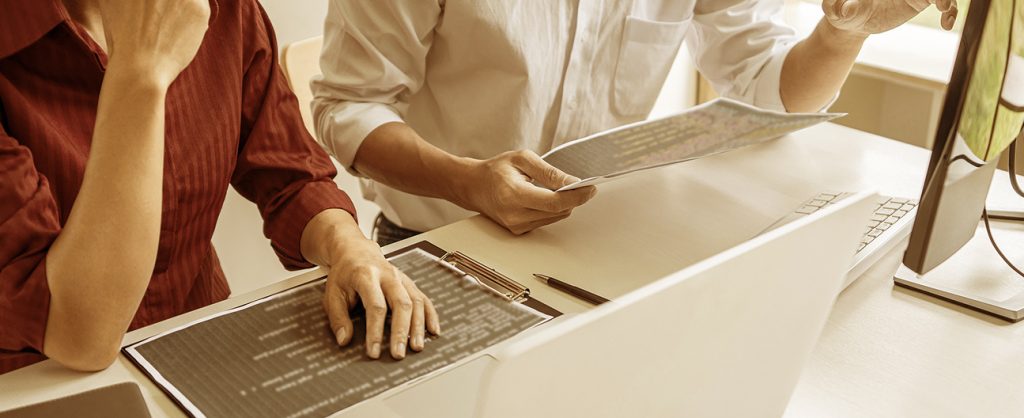 Two people working on an apartment web design on their computer and collaborating together.